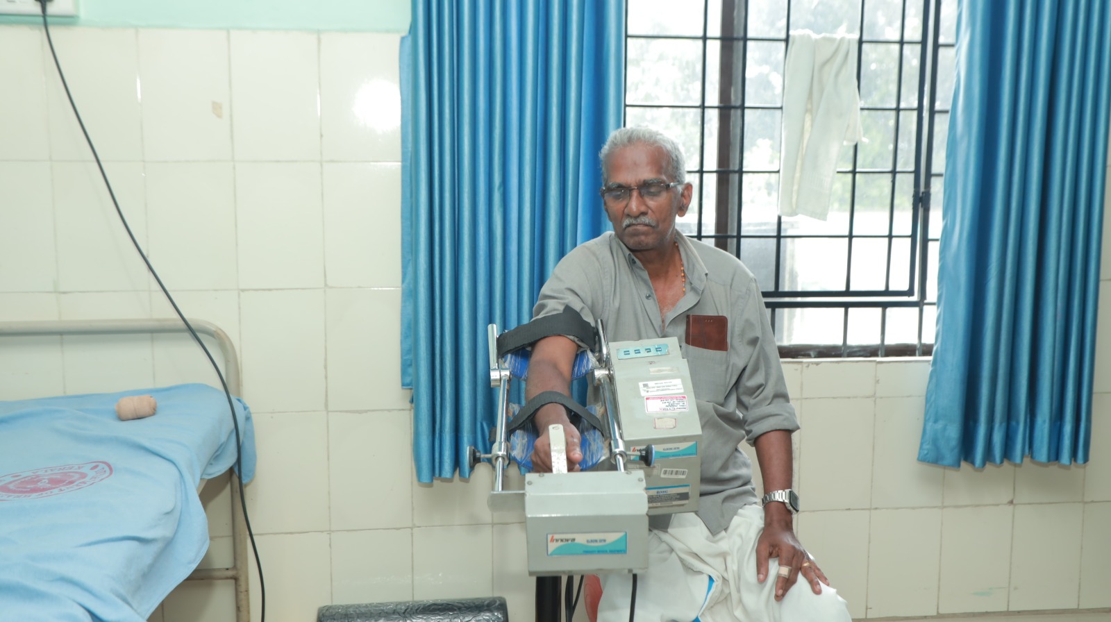 Hemophilia patient receiving aquatic hydrotherapy in indoor therapeutic pool at Kerala District Hospital with Indian physiotherapist supervising rehabilitation exercises